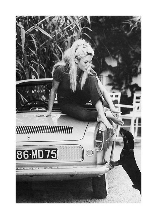  – Černobílá fotografie Brigitte Bardot natahující se z auta dolů ke psovi