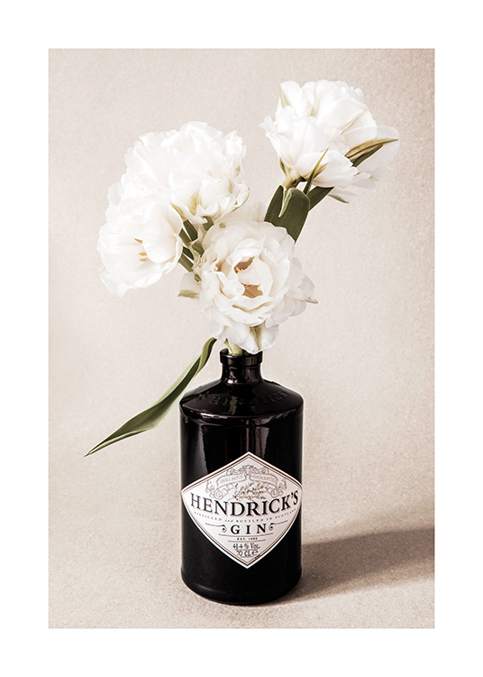  – Fotografie kytice bílých květin v černé láhvi od ginu na béžovém zrnitém pozadí
